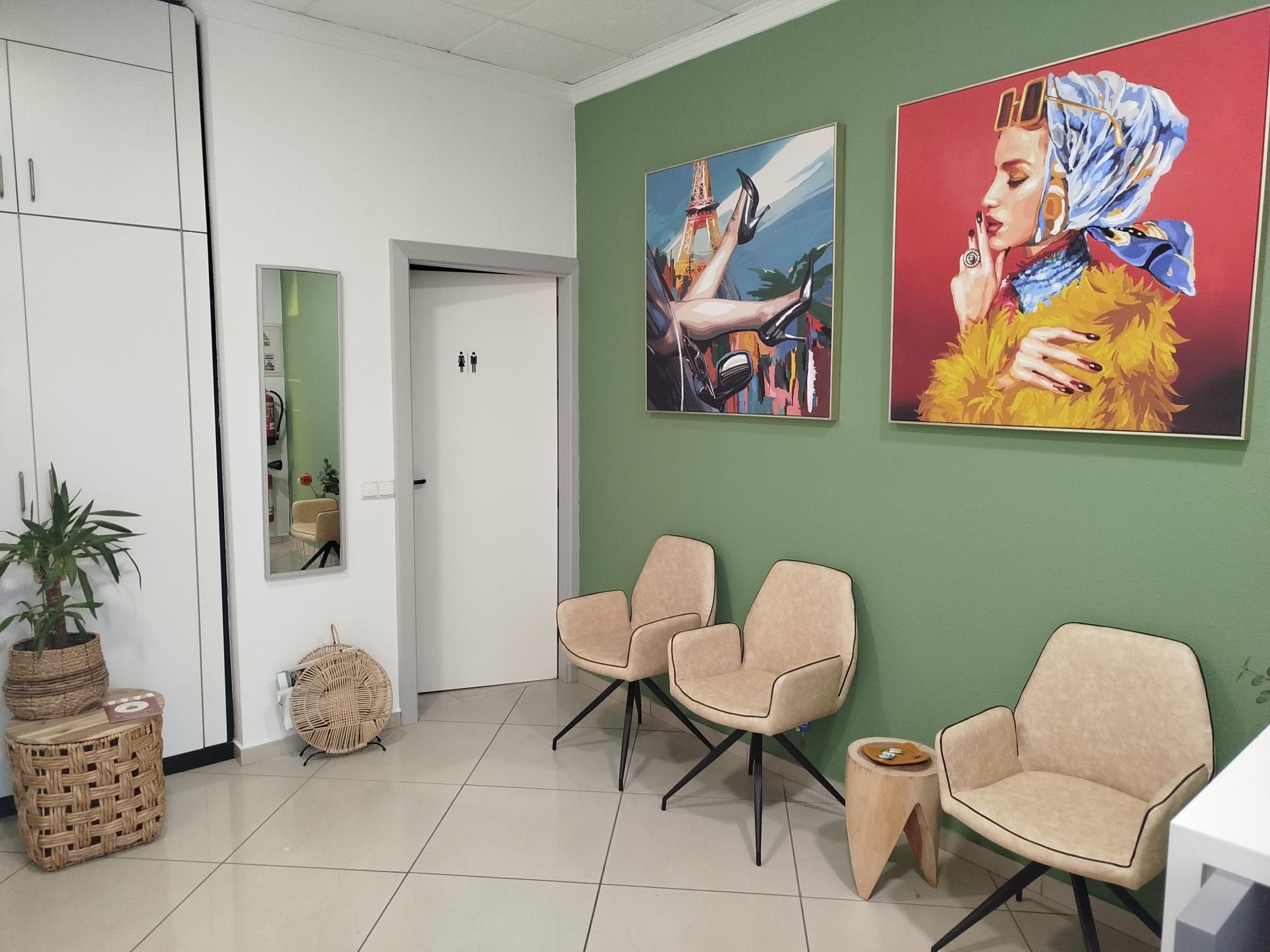 Sala de espera con sillones, plantas y cuadros sobre pared verde
